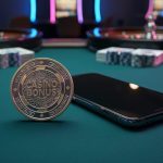 Casino felt table with a smartphone and a bonus token under neon-like reflections, with blurred gaming equipment in the background